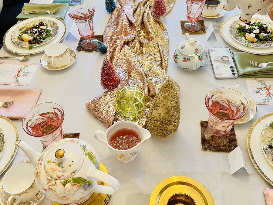 Una mesa dispuesta para una comida con varios platos, teteras y elementos decorativos.