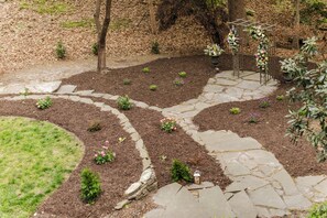 A garden with stone pathways, small plants, and a pergola with flowers. - Colonial Gardens (Williamsburg)