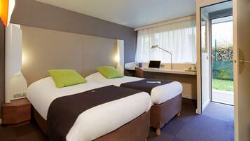 A hotel room with two beds, a desk, a laptop, and a view of the outdoors.