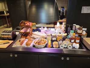 Un buffet de petit-déjeuner proposant un assortiment de viennoiseries, de pains et de condiments.
