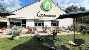 Un restaurant doté d’une terrasse, avec des tables et des chaises, et dont le logo est de couleur verte.