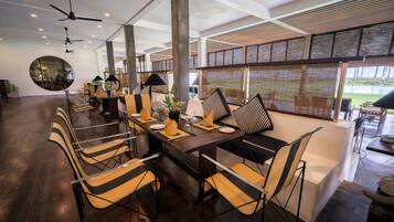 Un comedor moderno con una mesa larga, sillas y ventiladores de techo.
