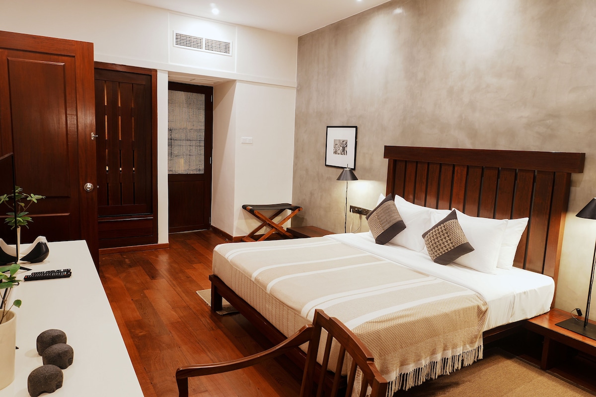 A hotel room with a wooden bed, bedside tables, a desk, and a chair.