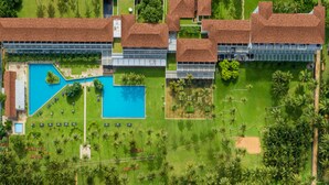 An aerial view of a resort with a large swimming pool, multiple buildings, and a beachfront. - The Blue Water - Geoffrey Bawa Heritage Resort Hotel (Wadduwa)