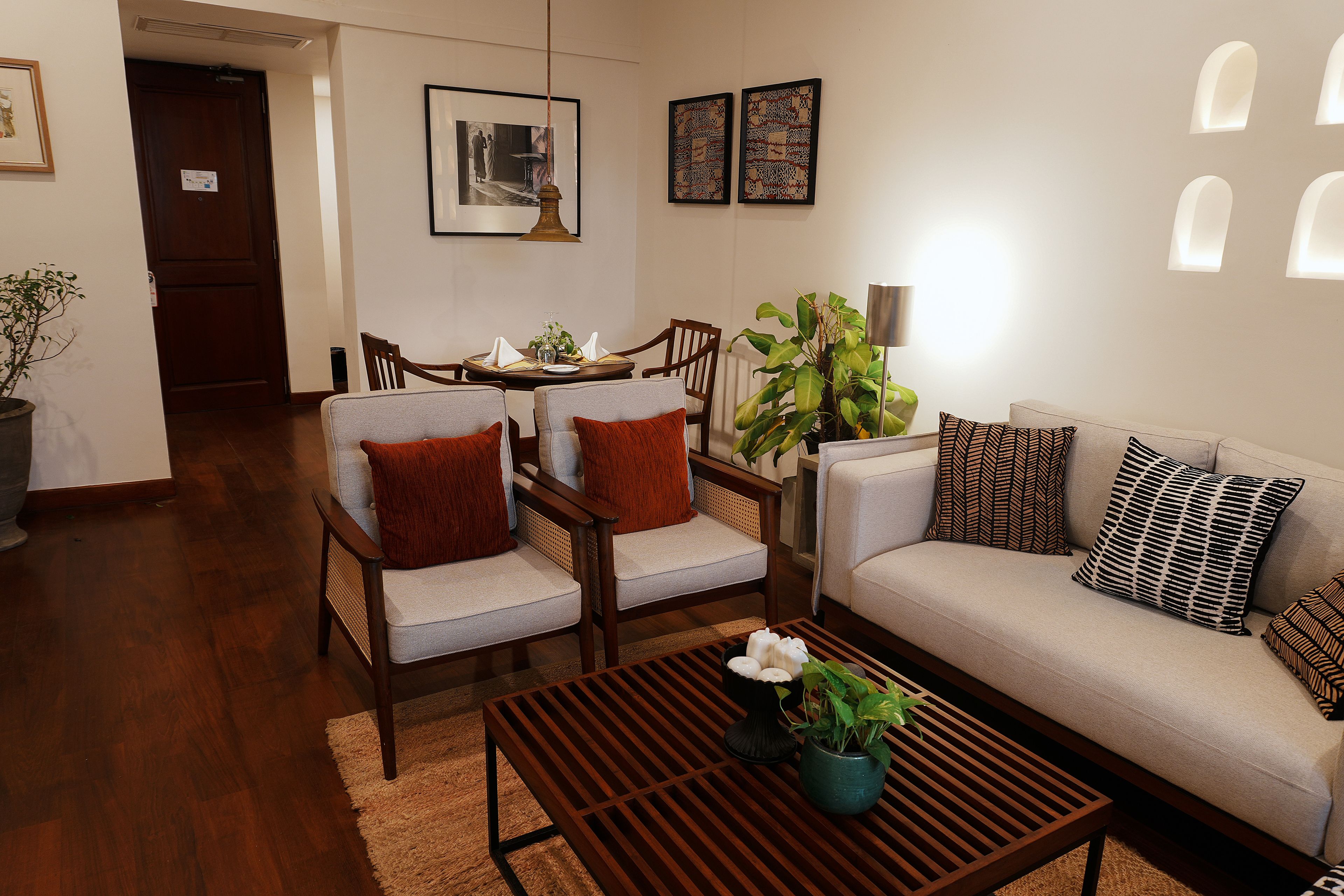 Una sala de estar con un sofá, dos sillones, una mesa de centro y un comedor con una mesa y sillas.
