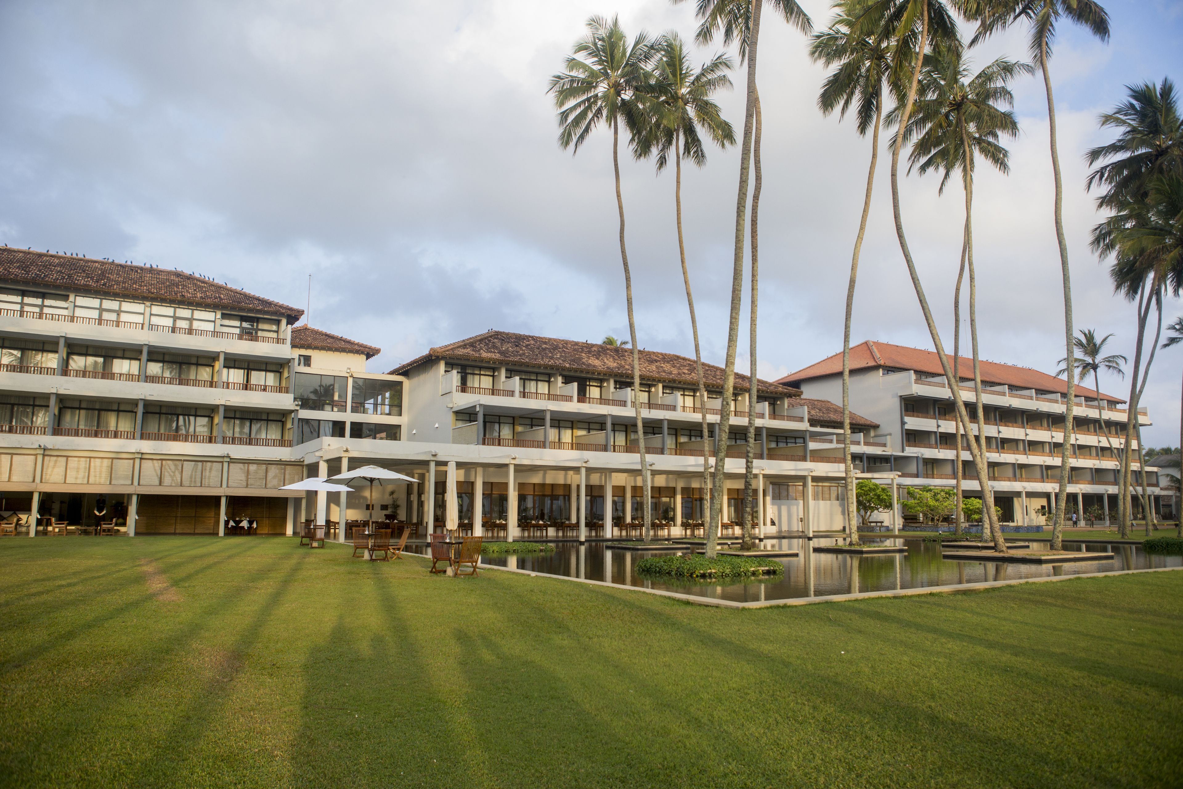 A multi-story hotel with a courtyard featuring palm trees and a pool.