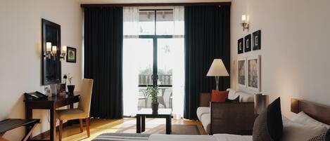 Une chambre d’hôtel avec un lit, un bureau, une chaise, une table avec une plante et un balcon avec vue.