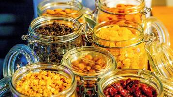 Una bandeja de madera con varios frascos de vidrio llenos de diversos alimentos.