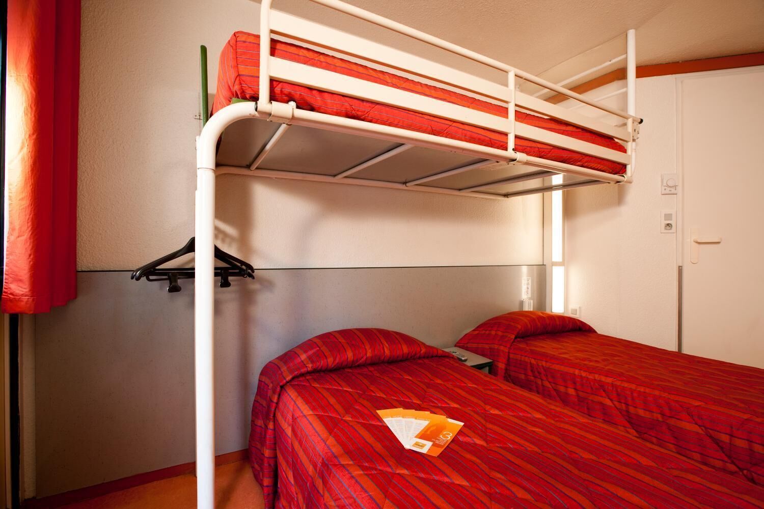 A bunk bed room with two beds, a wardrobe, and a coat rack.