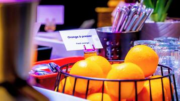 Un panier rempli d’oranges fraîches, étiqueté « Oranges à presser », avec un panneau indiquant qu’elles sont destinées à être pressées.