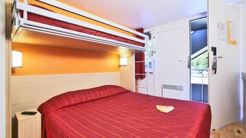 Ein kleines Zimmer mit einem Bett, einem Kleiderschrank und einer Tür zum Balkon.