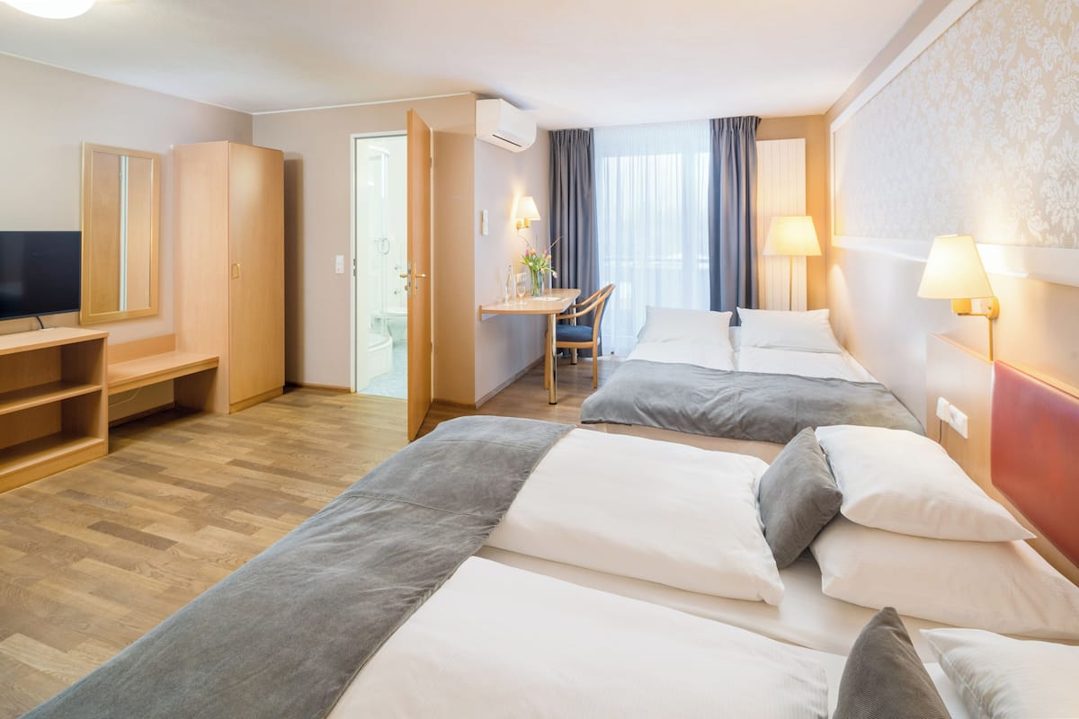 Ein Hotelzimmer mit zwei Betten, einem Schreibtisch, einem Stuhl, einem Fernseher und einem Kleiderschrank.