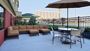 A patio with a sectional sofa, dining table, and chairs, overlooking a parking area and a hotel building. - Comfort Inn & Suites adj to Akwesasne Mohawk Casino (Hogansburg)