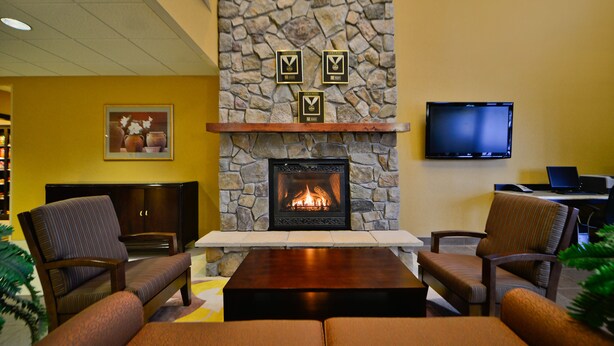 A cozy lobby with a stone fireplace, comfortable seating, a flat-screen TV, and a framed picture on the wall. - Comfort Inn & Suites adj to Akwesasne Mohawk Casino (Hogansburg)
