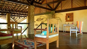 A room with a wooden bed, a wooden chair, a small table, and a decorative mirror on the wall. - Pousada Aguas de Paratii (Paraty)