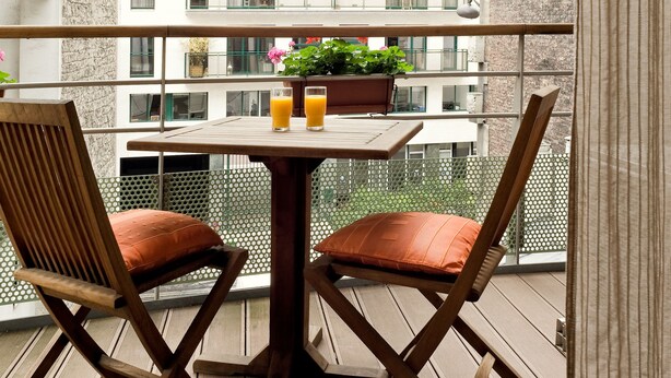 Un balcone con un tavolo, due sedie e una pianta in vaso.