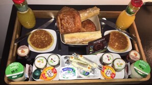 Un vassoio per la colazione con pancake, uova strapazzate, pane tostato, burro, marmellata e diverse creme.