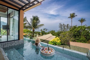 A pool area with a floating bar, palm trees, and a view of the mountains. - Aonang Princeville Villa Resort and Spa -GHA WellHotel-beachfront (Krabi)