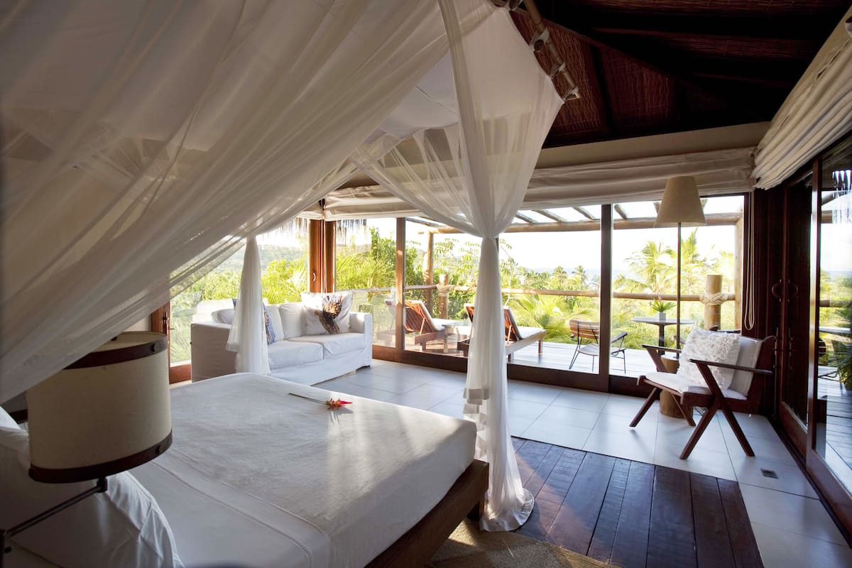 A bedroom with a bed, a bedside table, a sofa, and a chair.