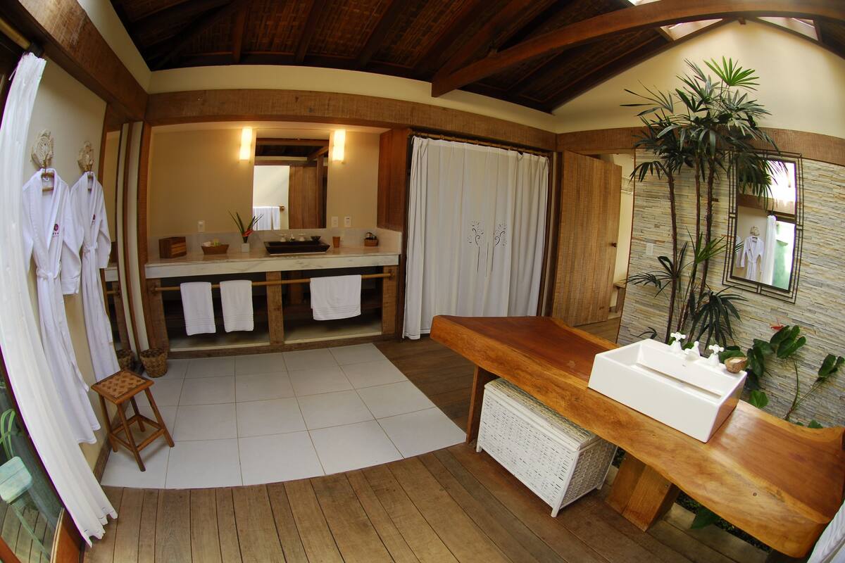 A bathroom with a wooden bench, a sink, and a mirror.