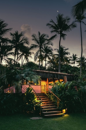 Um resort tropical com uma escadaria que leva a um prédio, rodeado por palmeiras e vegetação exuberante.