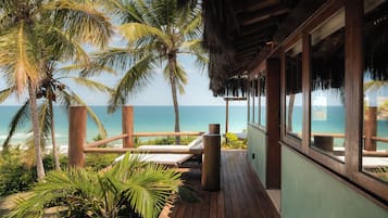 Una terraza de madera con vista al océano y palmeras.