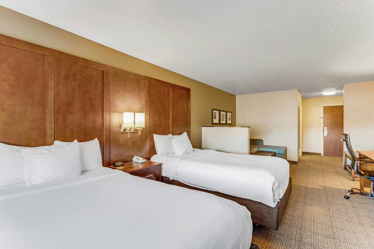 Une chambre d’hôtel avec deux lits, un bureau, une chaise et une petite table.
