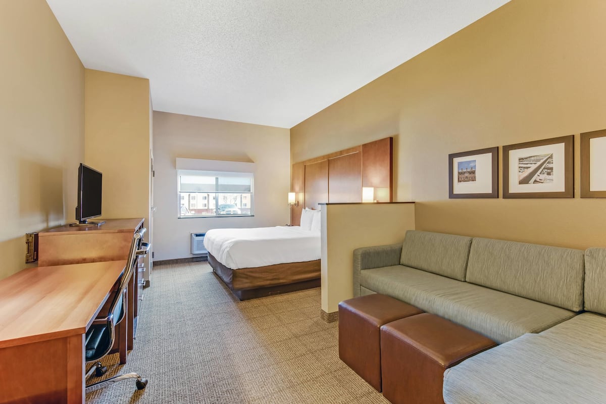 Une chambre d’hôtel avec un lit, un bureau, un canapé et une télévision.