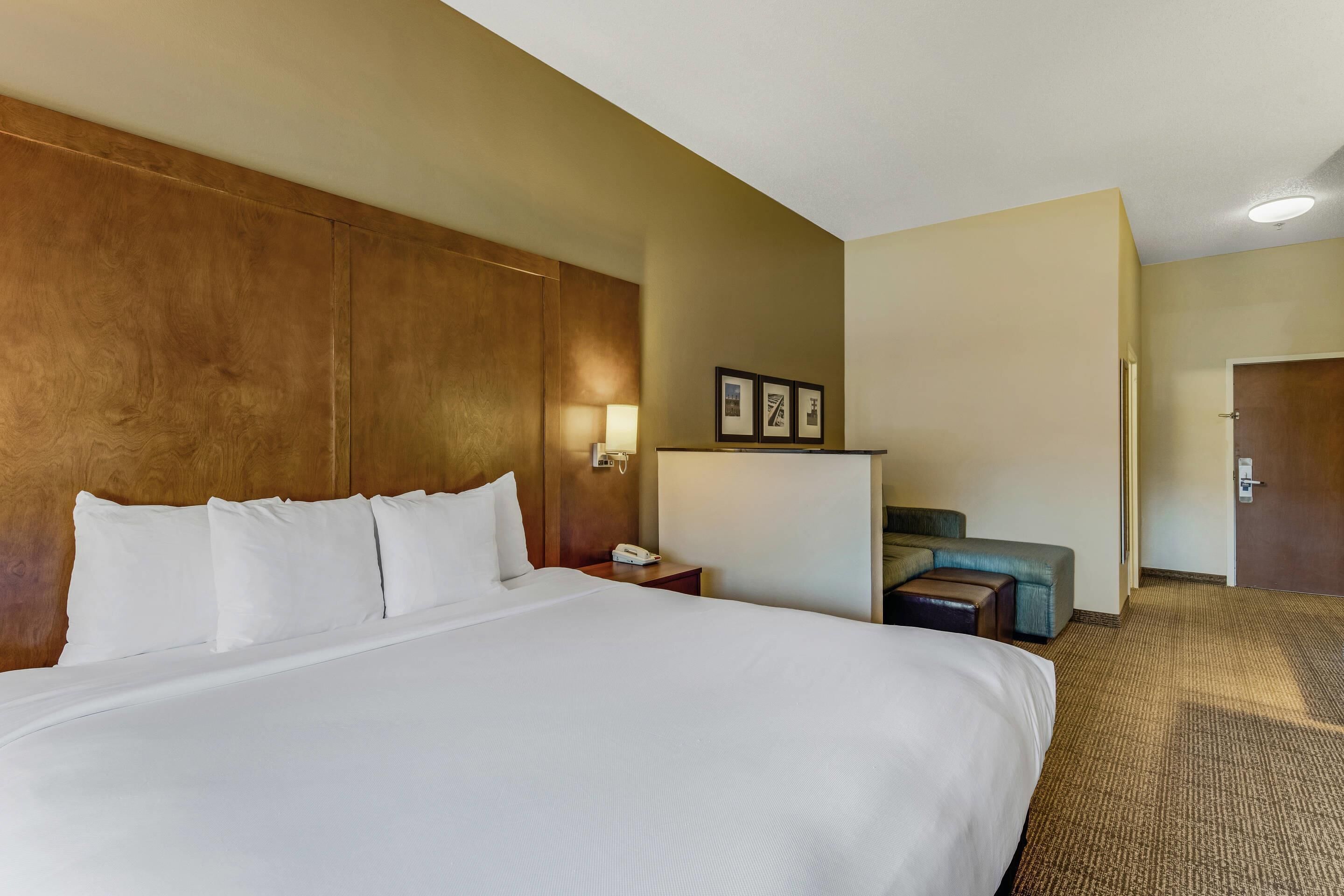 Ein Hotelzimmer mit einem großen Bett, einem Schreibtisch mit Lampe, einem Stuhl und einer Tür.