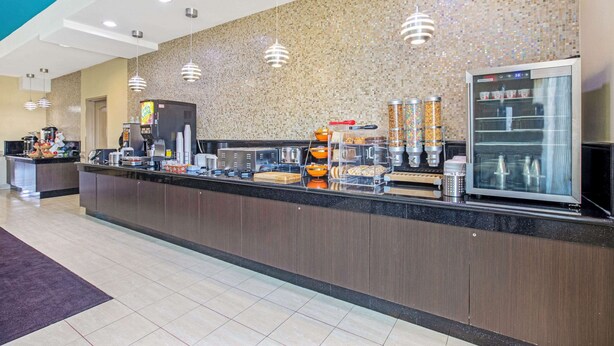 A modern hotel reception area with a counter, coffee machines, and a refrigerated display. - La Quinta Inn & Suites by Wyndham Corpus Christi Airport (Corpus Christi)