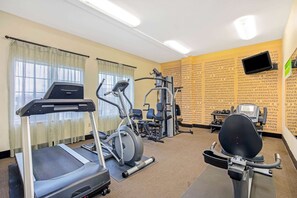 Une salle de sport équipée de tapis de course, de vélos elliptiques et de matériel de musculation.
