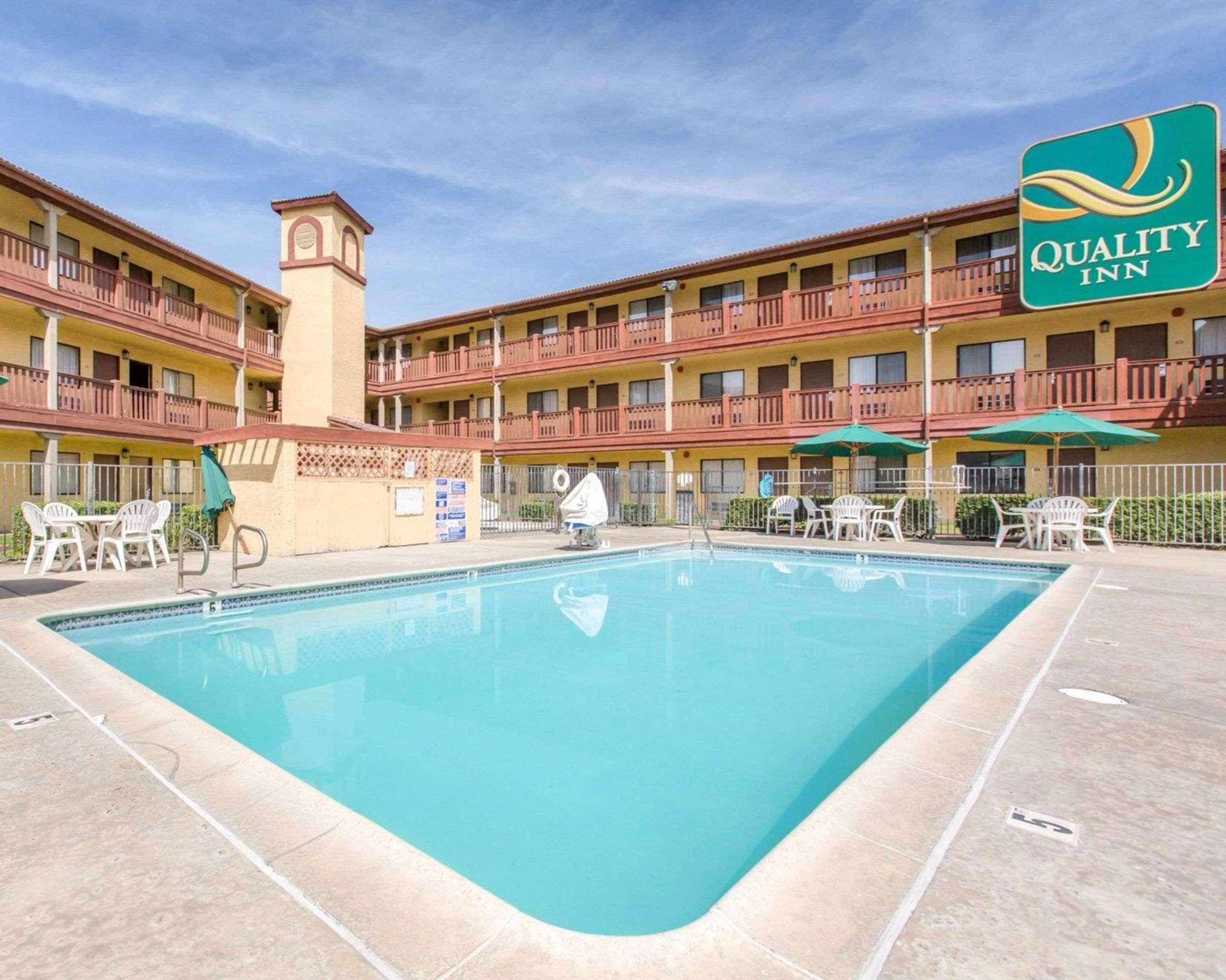 A hotel with a swimming pool, outdoor seating, and a sign for Quality Inn.