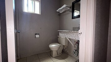 Un baño pequeño y funcional con inodoro, lavamanos y espejo.