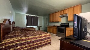 Una habitación con dos camas, kitchenette y televisión.