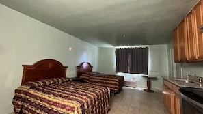A room with two beds, a small table, a window with curtains, and a kitchenette. - Executive Lodge Inn Stockton CA (Stockton)