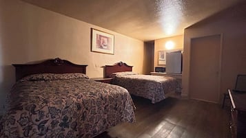 A hotel room with two beds, a small desk, and a mirror.