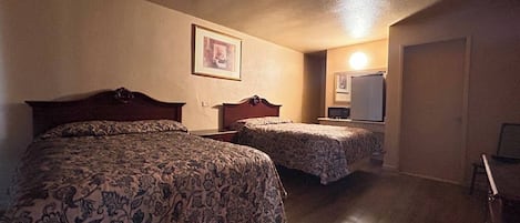 A hotel room with two beds, a small desk, and a mirror.