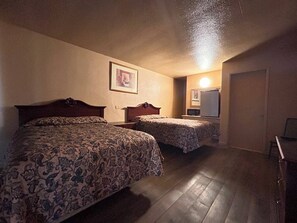 Una camera d'albergo con due letti, una piccola scrivania e uno specchio.
