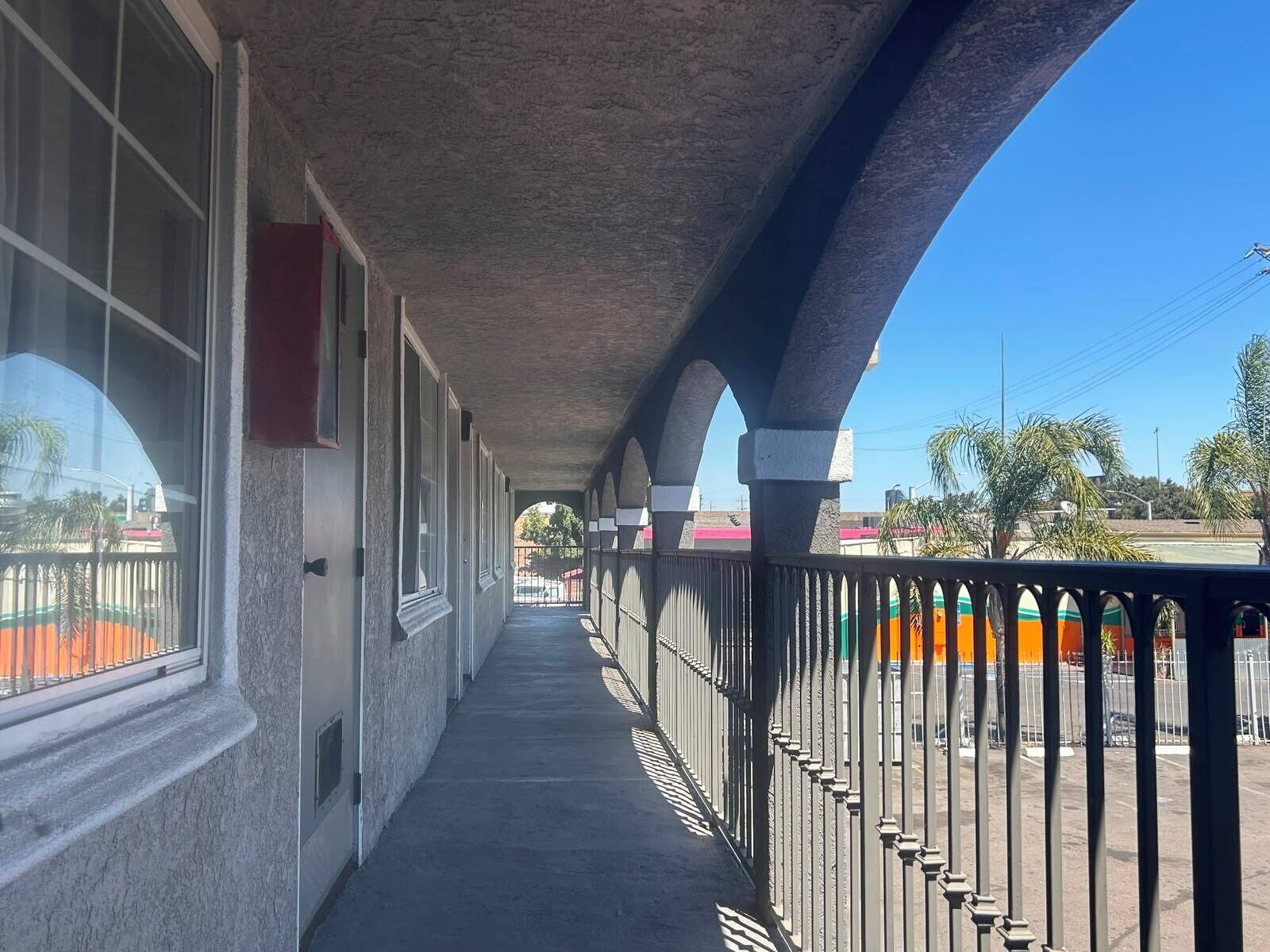 A covered corridor with windows and a railing overlooking a street.