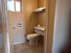 A small bathroom with a toilet, a sink, and a window. - Executive Lodge Inn Stockton CA (Stockton)