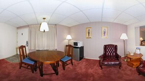 A conference room with a wooden table, blue cushioned chairs, a leather armchair, a desk with a telephone, and a microwave. - Rodeway Inn & Suites Pronghorn Lodge Lander (Lander)