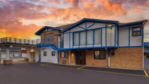 A motel with a two-story structure, a covered parking area, and a staircase leading to the upper level. - Rodeway Inn Lyons - La Grange (Lyons)