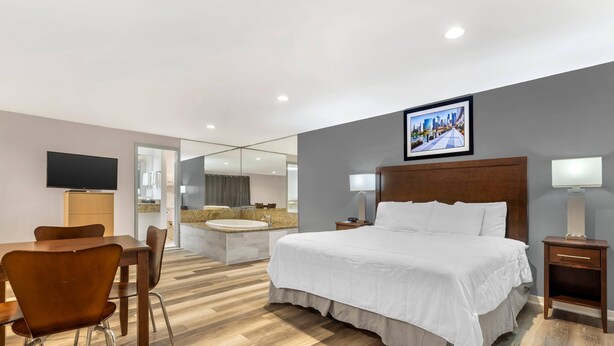 A modern hotel room with a large bed, a desk, and a seating area. - Rodeway Inn Lyons - La Grange (Lyons)