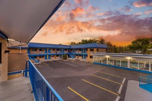 A motel with a blue and white exterior, a parking lot, and a pool area.