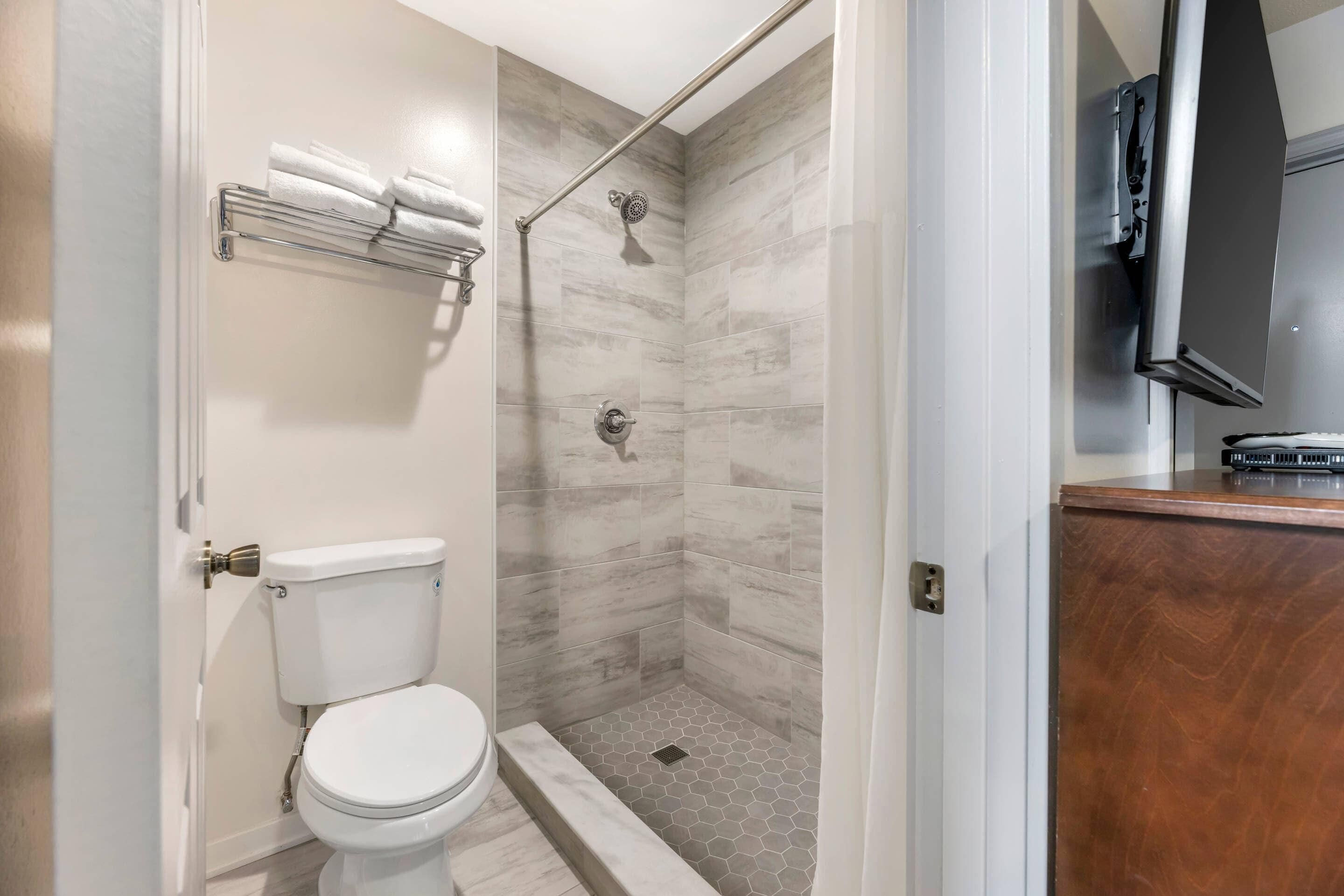 A bathroom with a toilet, shower, and a towel rack.