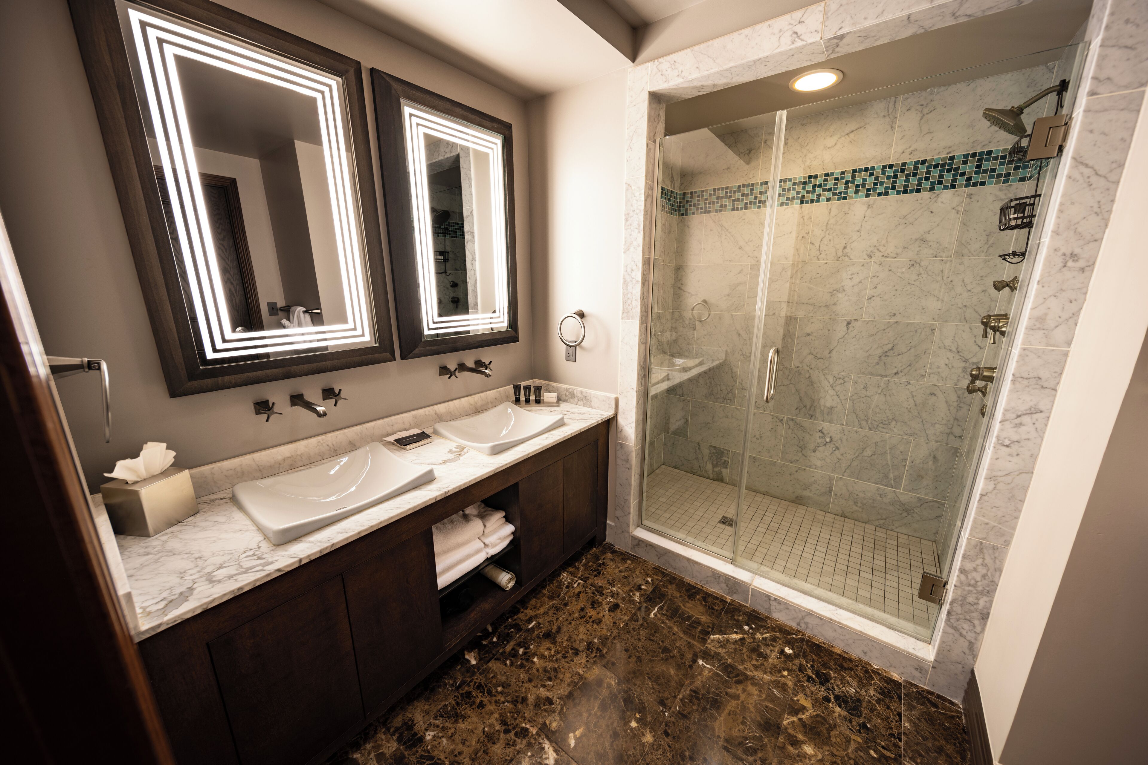 A bathroom with two sinks, a mirror, and a shower.