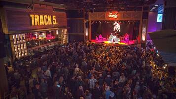 A crowded indoor venue with a stage and a bar area labeled 'TRACK 5'.