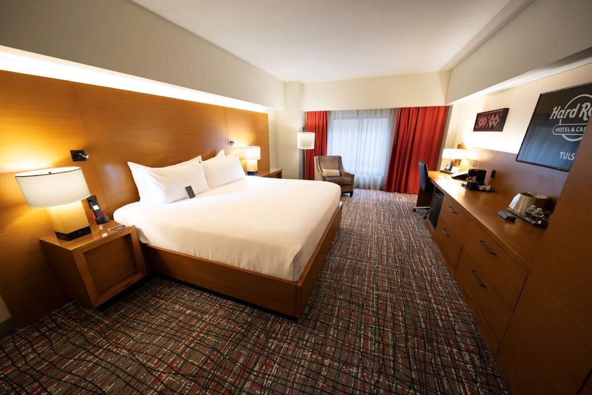 Habitación de hotel con una cama grande, un escritorio con computadora, una silla y un televisor.