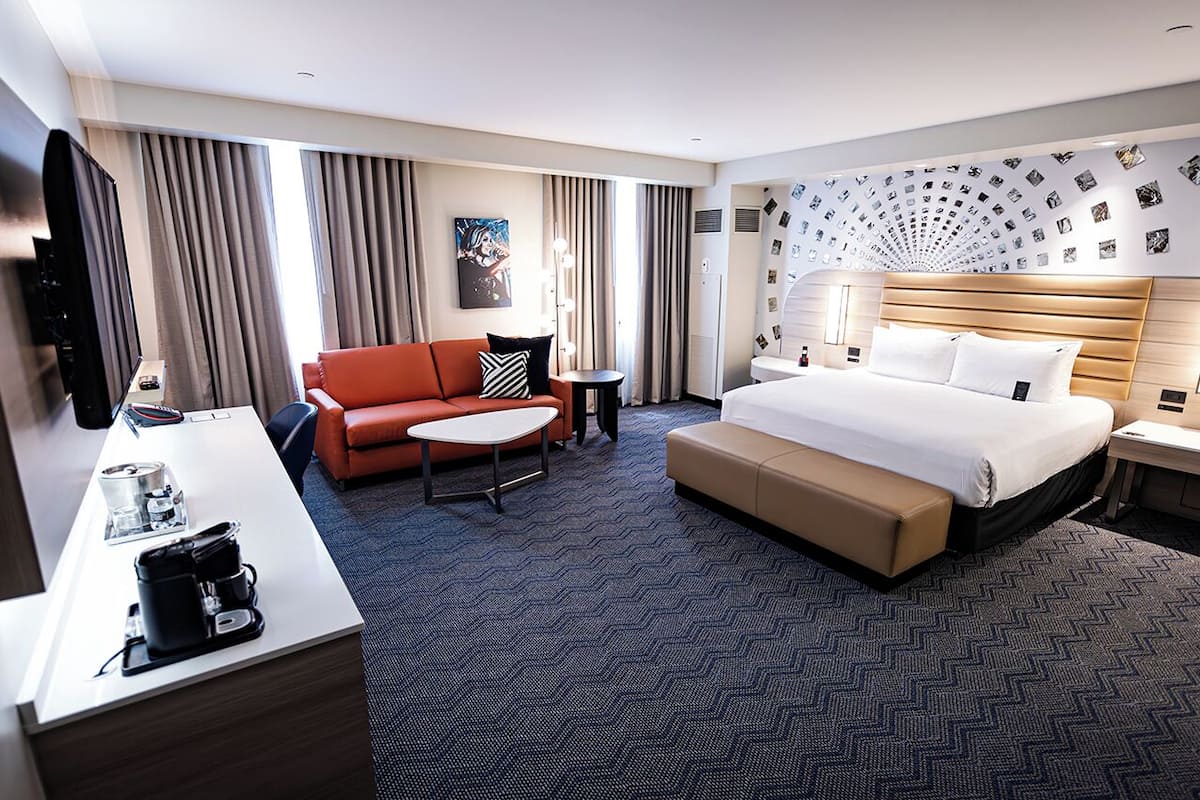 Habitación de hotel con cama, sofá, escritorio y cafetera.