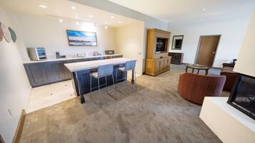 A modern kitchen with a bar area, a dining table, and a cozy seating area with a fireplace.